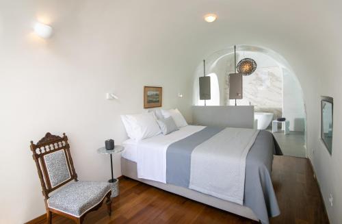 a bedroom with a large bed and a chair at Aloia Villas in Oia