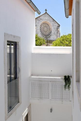 a window in a white building with a church at Villa Graça -Hostels and Apartments in Santarém