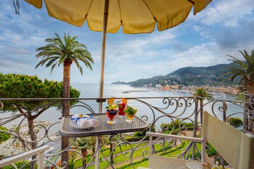 a table with drinks and an umbrella on a balcony at Hotel Continental in Santa Margherita Ligure