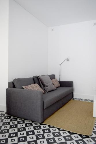 a grey couch in a room with a white wall at Villa Graça -Hostels and Apartments in Santarém