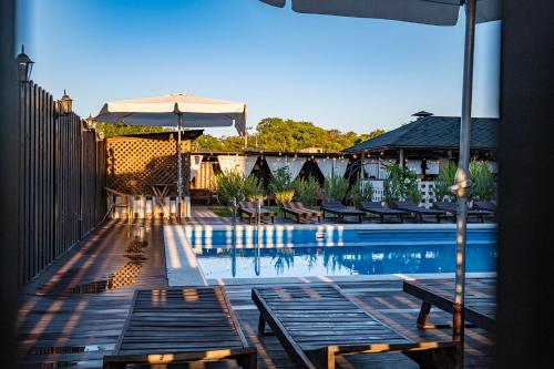 una piscina con bancos y sombrilla en Rezidenzia Utrish Hotel, en Sukko