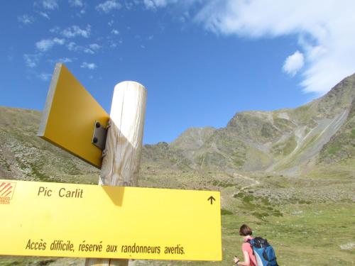 a man walking past a yellow sign in the mountains at Gîte de Llo - Vue Pyrénées, chambres & PDJ inclus in Llo