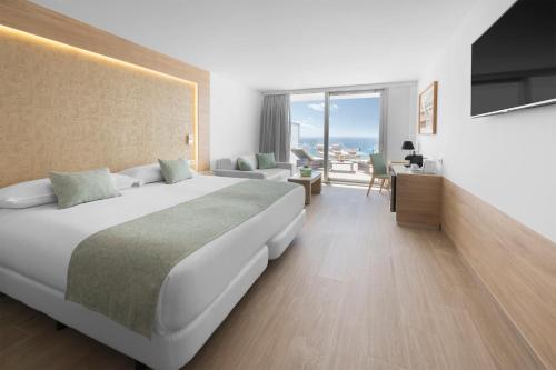 Elba Sunset Mallorca Thalasso Spa في بالمانوفا: غرفة نوم بسرير كبير وغرفة معيشة