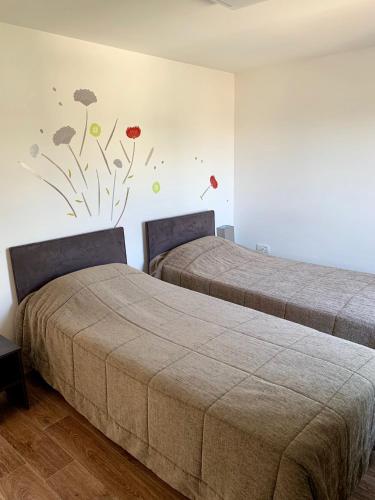 - 2 lits dans une chambre ornée de fleurs peintes sur le mur dans l'établissement Les Terrasses de l'Océan, à Saint-Hilaire-de-Riez