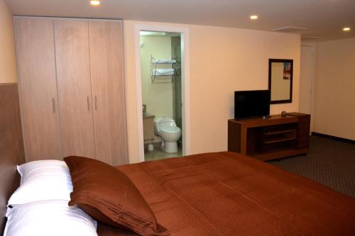 a bedroom with a bed and a bathroom with a toilet at Los Angeles Stay Inn in Quito