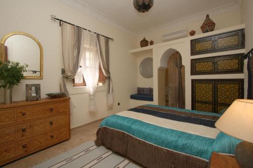 a bedroom with a bed and a dresser and a mirror at Riad petit Karmela in Marrakesh