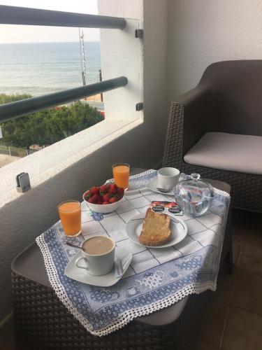 a table with a breakfast of coffee and fruit on a balcony at Apartamento Praia Da Gaivota in Quarteira