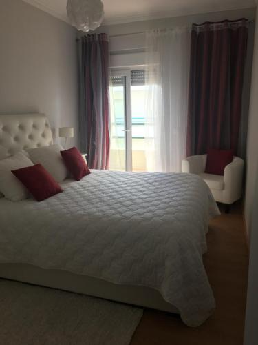 a bedroom with a large white bed with red pillows at Apartamento Praia Da Gaivota in Quarteira