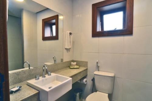 uma casa de banho com um lavatório, um WC e um espelho. em Hotel Magique Le Canton em Teresópolis