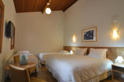 Cette chambre comprend 2 lits et une table. dans l'établissement Hotel Magique Le Canton, à Teresópolis