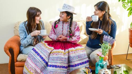 a group of three women sitting on a couch drinking coffee at Sonqo Killa del Colca in Chivay