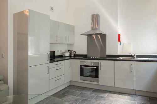 a kitchen with white cabinets and a stove at The Castle Collection 14 Cook Street in Liverpool