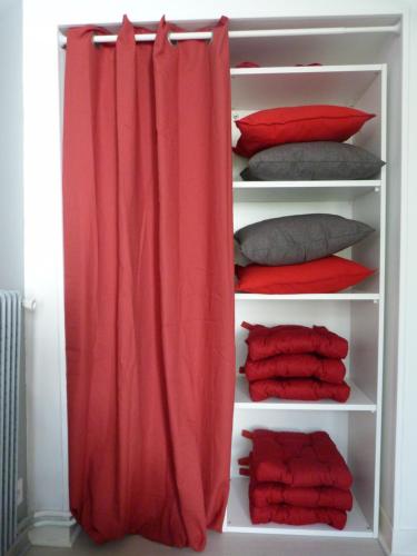 Armario con cortina roja y almohadas en Appartement cosy à 10 minutes de Chambord, en Mer