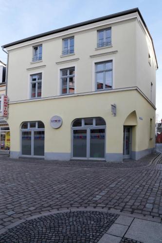 a large white building on a cobblestone street at Pension am Pferdemarkt in Güstrow