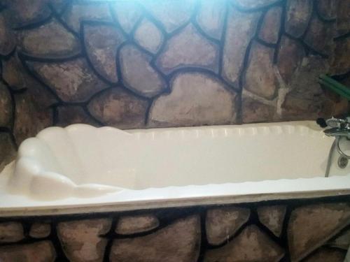 une baignoire blanche dans un mur en pierre dans l'établissement Tembo Safari Lodge, à Katunguru