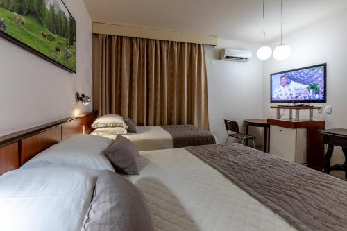 a hotel room with two beds and a flat screen tv at Aguas do Iguaçu Hotel Centro in Foz do Iguaçu