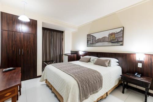 a hotel room with a bed and a desk at Aguas do Iguaçu Hotel Centro in Foz do Iguaçu