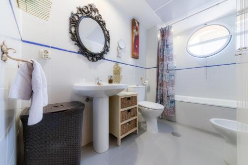 a bathroom with a sink and a toilet and a mirror at Ático parque Kotinoussa in Cádiz