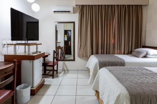 a hotel room with two beds and a flat screen tv at Aguas do Iguaçu Hotel Centro in Foz do Iguaçu