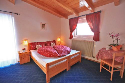 a bedroom with a bed with red pillows and a window at Hotel Vigo in Vigo di Fassa