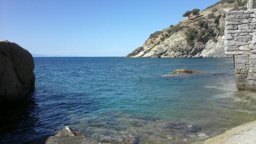 a large body of water next to a rocky mountain at Appartamento Il Mandarino in Pomonte
