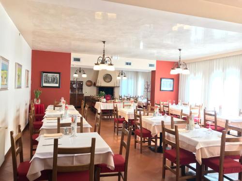 un restaurante con mesas y sillas blancas y paredes rojas en Al Cavallino, en Follina