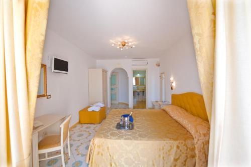 a room with a bed and a table and a desk at Hotel Villa Maria Pia in Praiano