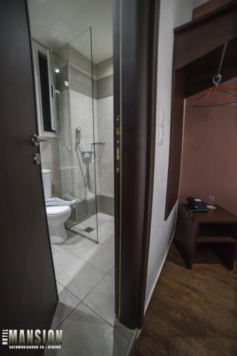a bathroom with a toilet and a glass shower at Mansion Hotel in Athens