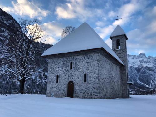 an old stone church with a snow covered roof at Bujtina Ziçi in Theth