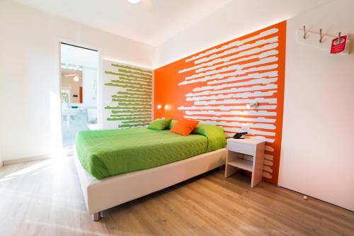 a bedroom with a green bed and an orange wall at All'Orologio - Boutique Hotel in Caorle