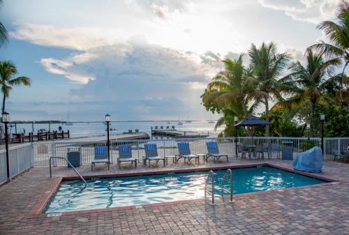 a swimming pool with chairs and a view of the ocean at Bayside Inn Key Largo in Key Largo