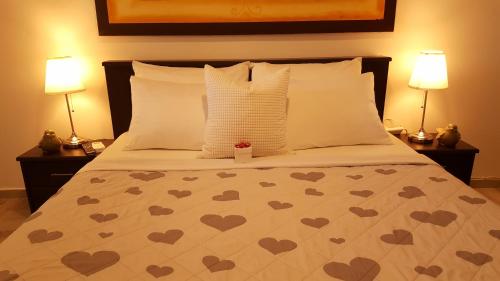a bed with hearts on it with two lamps at By The Sea Vacation Suite in Ashqelon