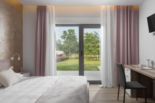 a bedroom with a bed and a desk and a window at Villa Helios in Sveti Petar u Šumi