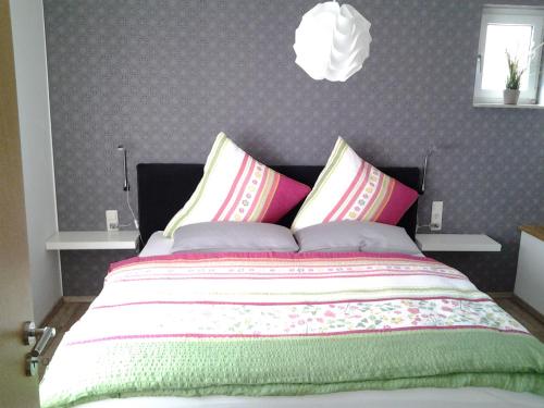 ein Schlafzimmer mit einem großen Bett mit bunten Kissen in der Unterkunft Ferienhaus Schloss-Garten in Kapellen-Drusweiler