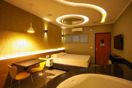 a bedroom with a bed and a bath tub and a sink at Oasis Motel in Piracicaba