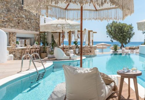 ein Resortpool mit Stühlen und einem Tisch in der Unterkunft Virtu Suites in Agios Prokopios