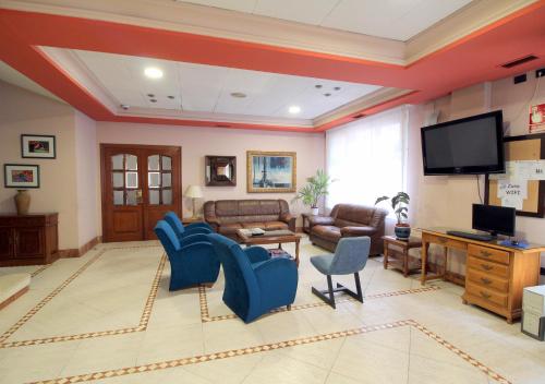 sala de estar con sillas azules y TV de pantalla plana en Hotel Doña Nieves, en Noreña