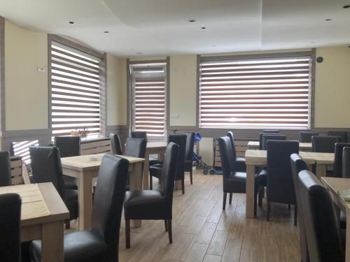 a dining room with tables and chairs and windows at Vila Zlatarka in Nova Varoš