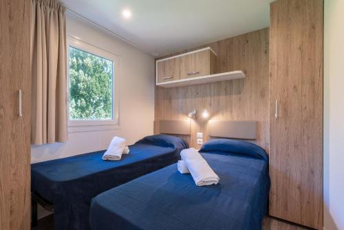 due letti blu in una stanza con una finestra di Camping Village Panoramico Fiesole a Fiesole
