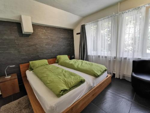 a bedroom with a large bed with green pillows at Apartments Steinbock in Leukerbad