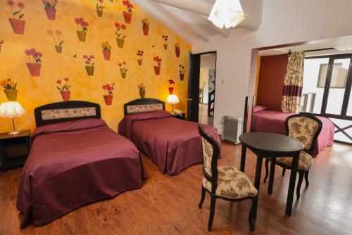 a room with three beds and a table and chairs at Tika Wasi Casa Boutique in Cusco