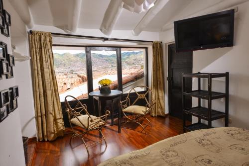 um quarto com uma mesa e cadeiras e uma grande janela em Tika Wasi Casa Boutique em Cusco