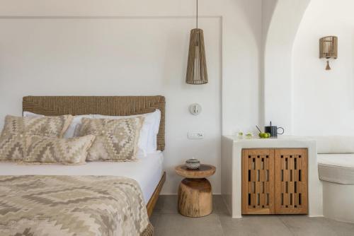 a white bedroom with a bed and a table at Virtu Suites in Agios Prokopios