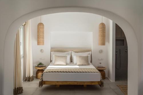 a white bedroom with a large bed with white pillows at Virtu Suites in Agios Prokopios