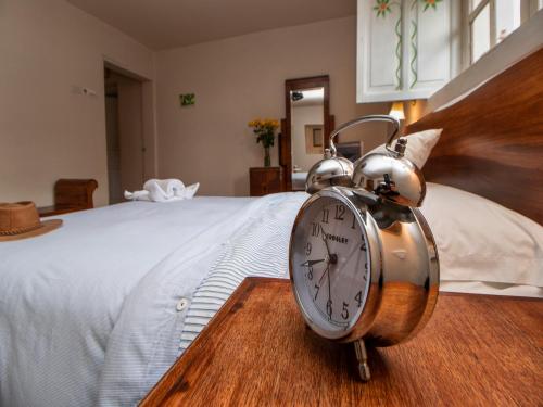 a clock sitting on top of a bed at Hosteria Papagayo Cotopaxi in Machachi