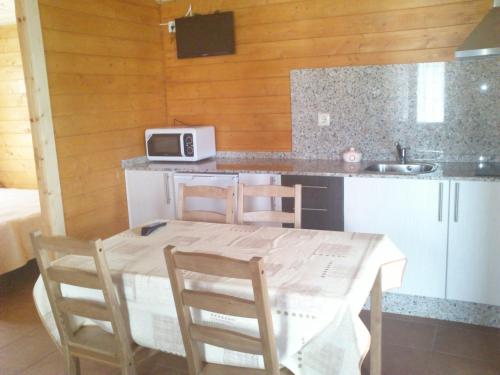 a kitchen with a table and chairs and a microwave at Camping Paxariñas in Portonovo