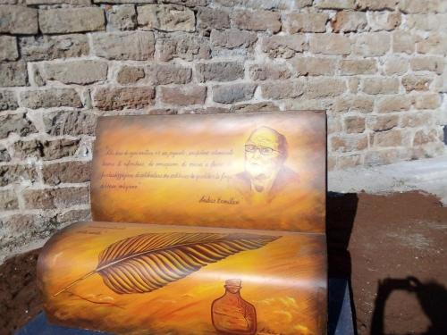 a painting of a man sitting on a chair next to a brick wall at Terra Sinus Holiday House in Terrasini