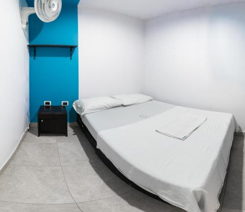 Cama blanca en habitación con pared azul en Hotel Oviedo Real, en Bucaramanga