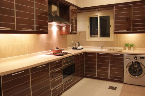 a kitchen with brown cabinets and a washer and dryer at Mandarin Alshamal Hotel Apartments in Riyadh