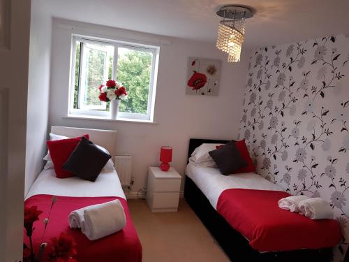 2 camas en una habitación con rojo y blanco en Vetrelax Basildon Crosse Apartment en Basildon